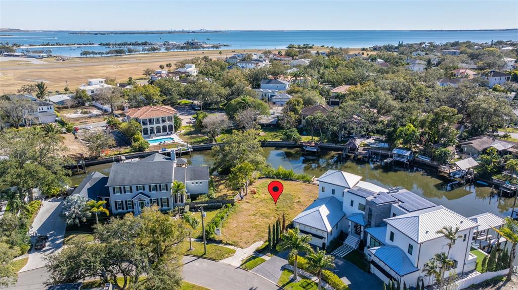 An aerial view shows a vacant waterfront lot situated between two large residential homes — 678 GENEVA PLACE, TAMPA, FL