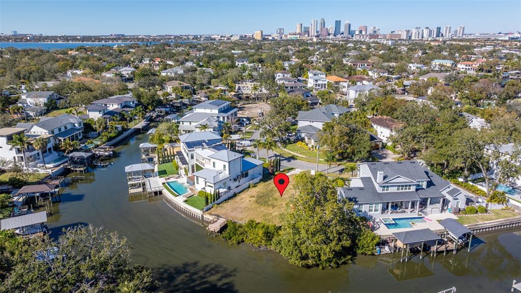 An aerial view shows a vacant waterfront lot situated between two large residential homes — 678 GENEVA PLACE, TAMPA, FL