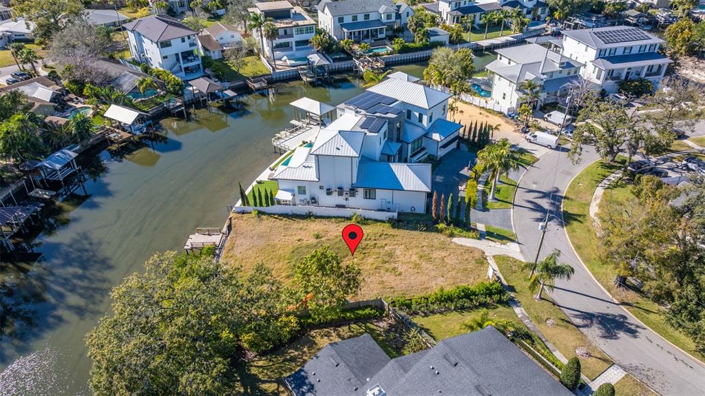 An aerial view shows a vacant waterfront lot next to a large modern house — 678 GENEVA PLACE, TAMPA, FL