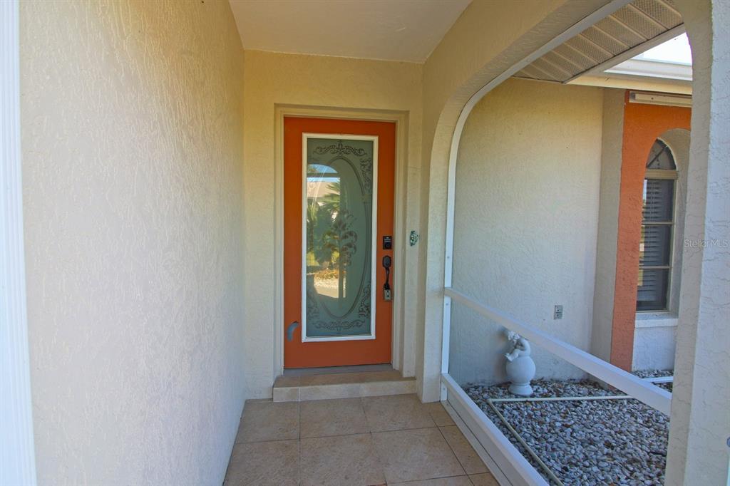A covered entryway features a bright orange front door with a decorative glass insert — 32 BARILOCHE DRIVE, PUNTA GORDA, FL