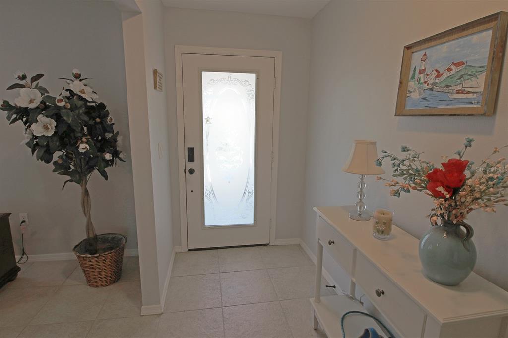 An entryway features a white front door with a decorative glass insert and tiled flooring — 32 BARILOCHE DRIVE, PUNTA GORDA, FL