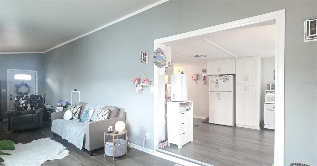 A living room with gray walls and flooring opens into a kitchen with white cabinets — 177 FOREST LAKE DRIVE, COCOA, FL