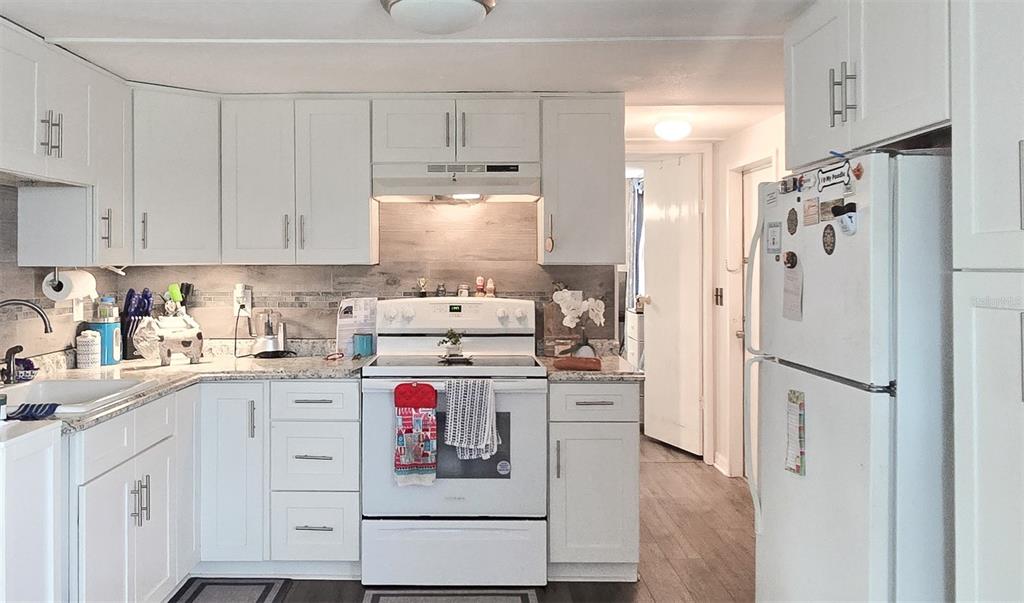 A kitchen features white cabinets, granite countertops, a white stove, and a white refrigerator — 177 FOREST LAKE DRIVE, COCOA, FL
