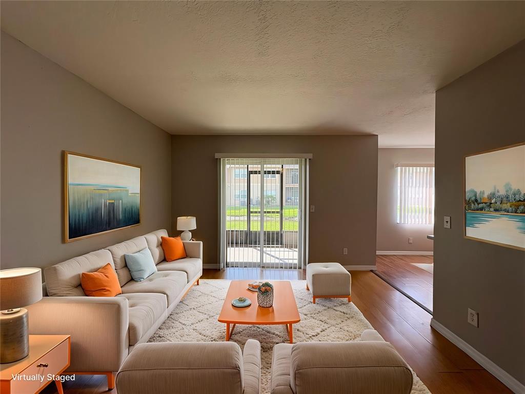 A living room with a beige sofa, orange coffee table, and sliding glass patio doors — 9933 SWEEPSTAKES LANE UNIT 6, ORLANDO, FL