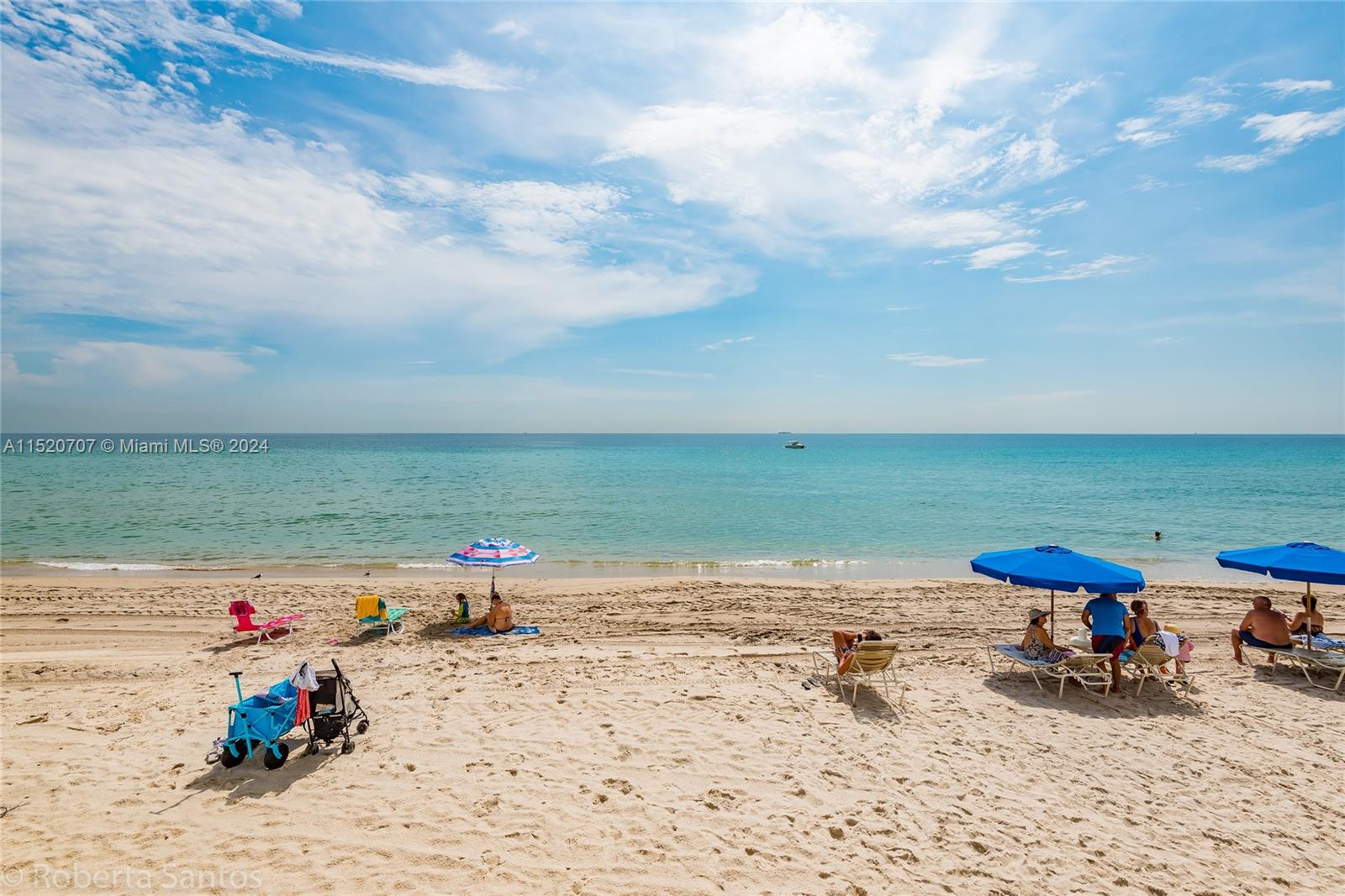 People relax under umbrellas on a sandy beach overlooking the ocean under a blue sky — 3180 S Ocean Dr # 422, Hallandale Beach FL 33009, HALLANDALE BEACH, FL
