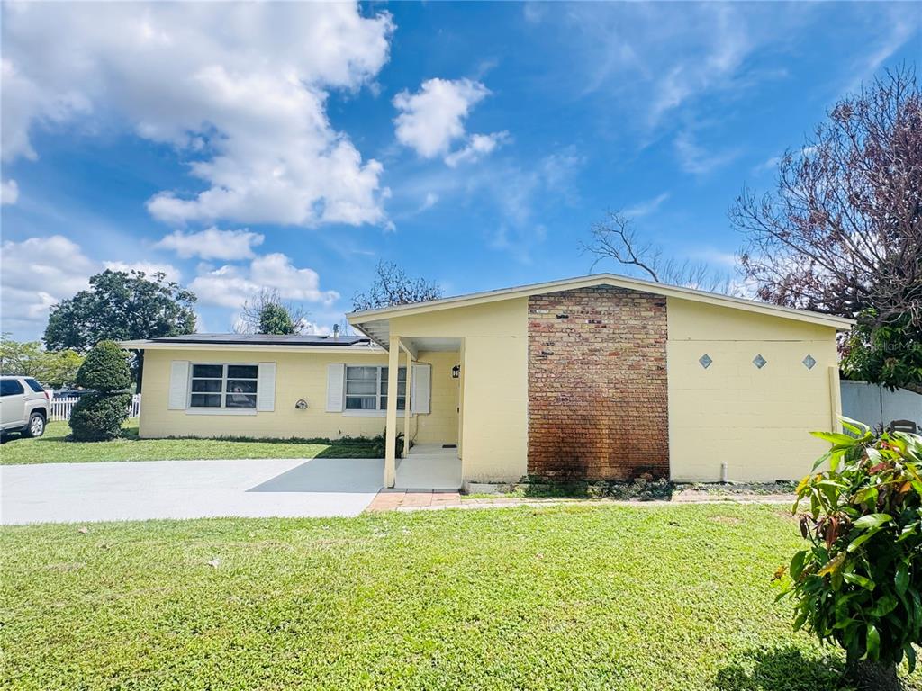 A yellow house exterior features a garage, a front door, and a small lawn — 767 FORESTER AVENUE, ORLANDO, FL
