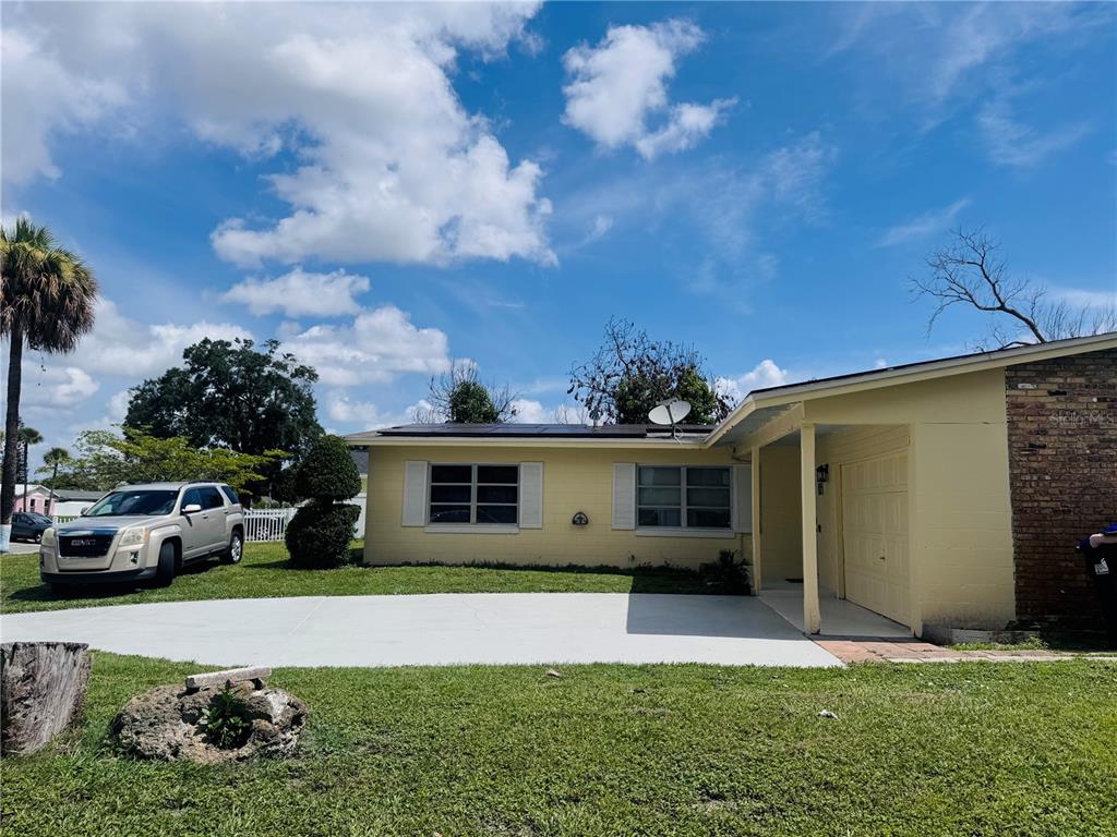 A yellow single-story house features a white front door, a garage, and a concrete driveway — 767 FORESTER AVENUE, ORLANDO, FL