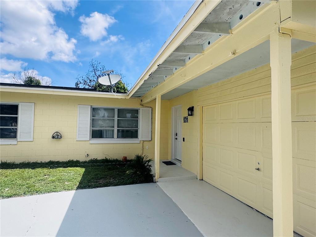 The exterior of a yellow, single-story concrete block house with two windows and a lawn — 767 FORESTER AVENUE, ORLANDO, FL