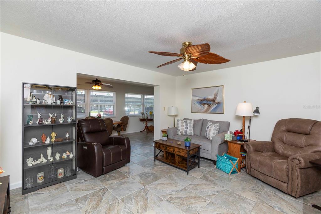 A living room with tile floors, a ceiling fan, a sofa, and two recliners — 4812 JASPER DRIVE UNIT 107, NEW PORT RICHEY, FL