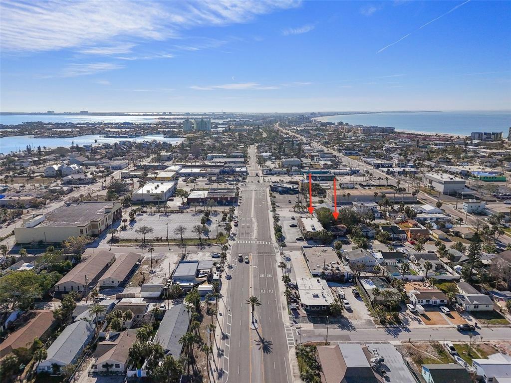 An aerial view shows a coastal town with a main road and two red arrows — 420 77TH AVENUE, ST PETE BEACH, FL
