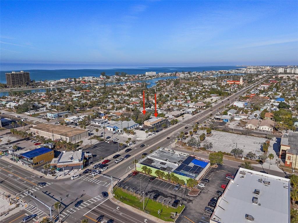 An aerial view shows a commercial building with red arrows pointing toward its roof — 420 77TH AVENUE, ST PETE BEACH, FL
