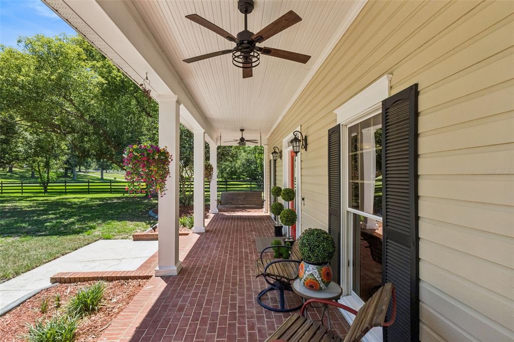A brick house with a covered front porch and a red door sits on a lawn — 14951 THOROUGHBRED LN, MONTVERDE, FL