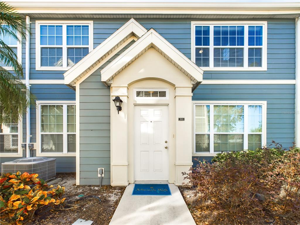 The exterior of a two-story blue building features a white front door and walkway — 5521 ROSEHILL ROAD UNIT 203, SARASOTA, FL