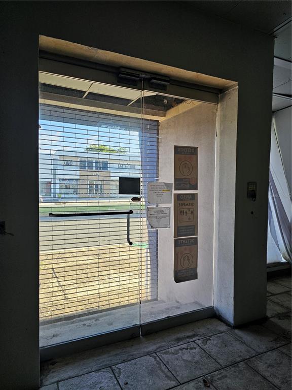 A glass storefront door with a security gate looks out onto a street and building — 151 FD ROOSEVELT AVE. AVENUE, SAN JUAN, PR