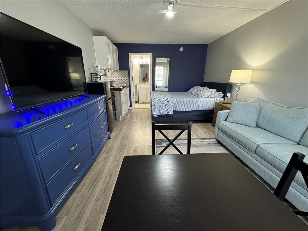 A studio apartment features a blue dresser, a bed, a sofa, and a small kitchenette — 7150 N TAMIAMI TRAIL UNIT S-623, SARASOTA, FL