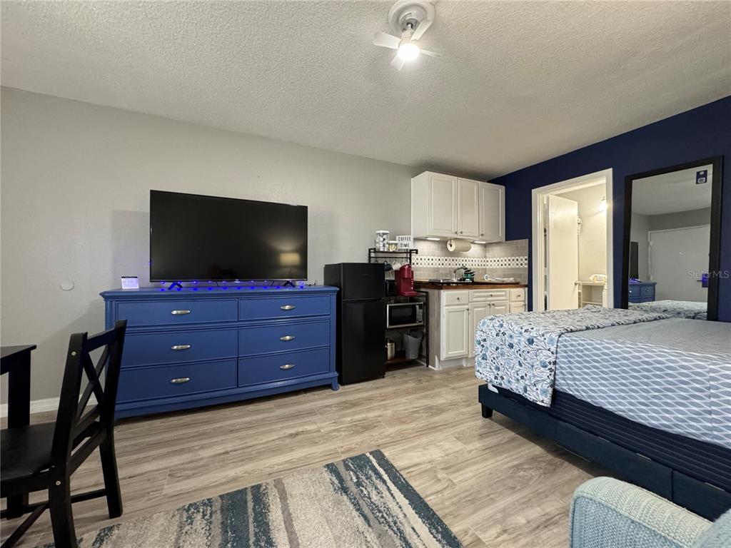A bedroom features a blue dresser, a television, a kitchenette, and a bed — 7150 N TAMIAMI TRAIL UNIT S-623, SARASOTA, FL
