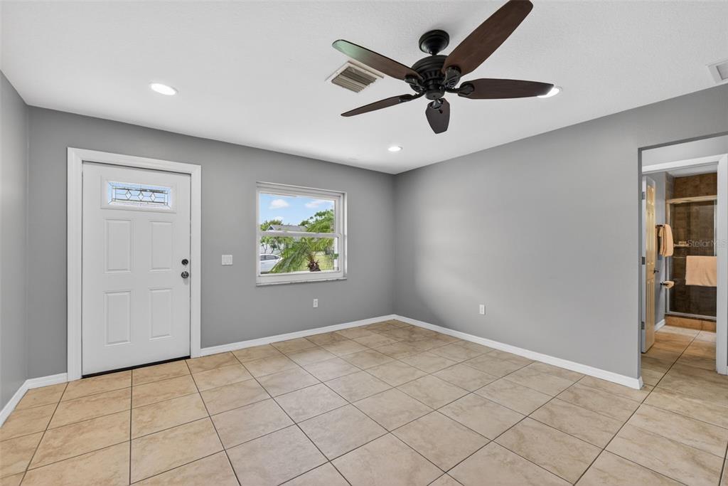 A room with gray walls, tile flooring, a ceiling fan, a white door, and a window — 10136 PEACH AVENUE, ENGLEWOOD, FL