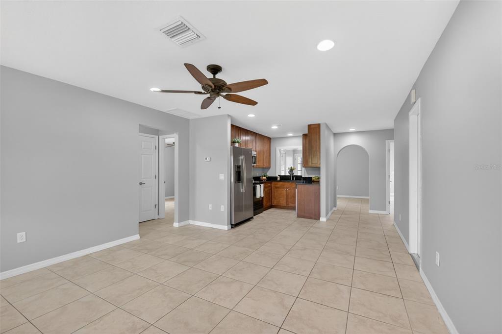 An open-concept room features light tile flooring, a ceiling fan, and a wood-cabinet kitchen — 10136 PEACH AVENUE, ENGLEWOOD, FL