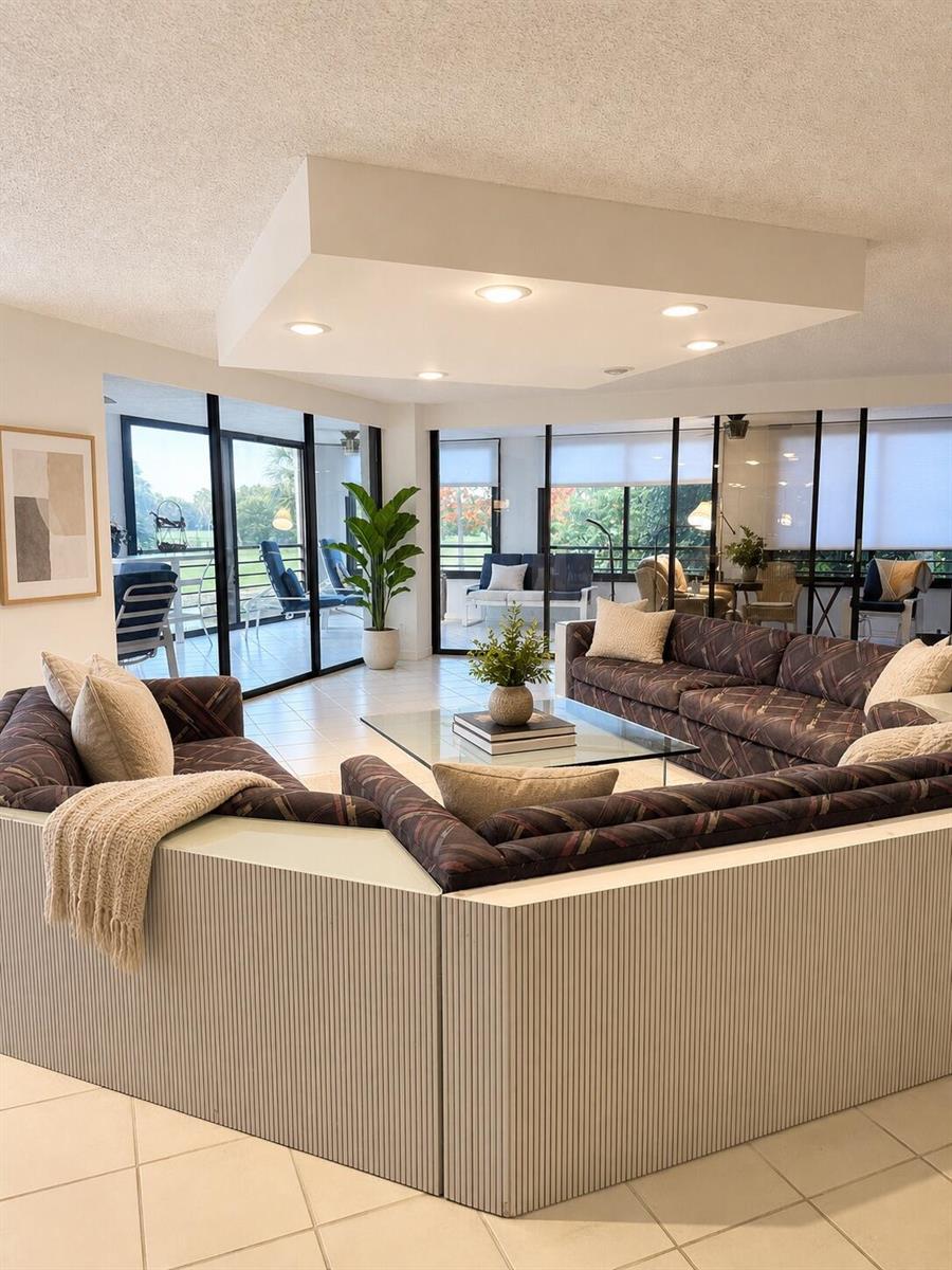 A living room features a large sectional sofa, a glass coffee table, and floor-to-ceiling windows — 7567 Imperial Drive # 202, Boca Raton FL 33433, BOCA RATON, FL