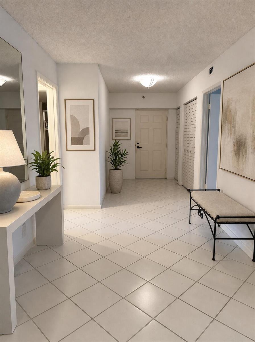 A bright entryway features white tile floors, a console table, a bench, and wall art — 7567 Imperial Drive # 202, Boca Raton FL 33433, BOCA RATON, FL