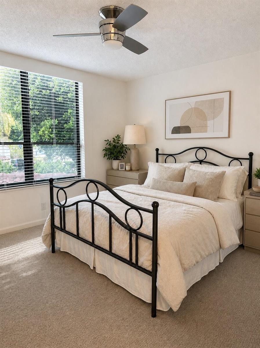 A bedroom features a black metal bed frame, neutral bedding, and a ceiling fan — 7567 Imperial Drive # 202, Boca Raton FL 33433, BOCA RATON, FL