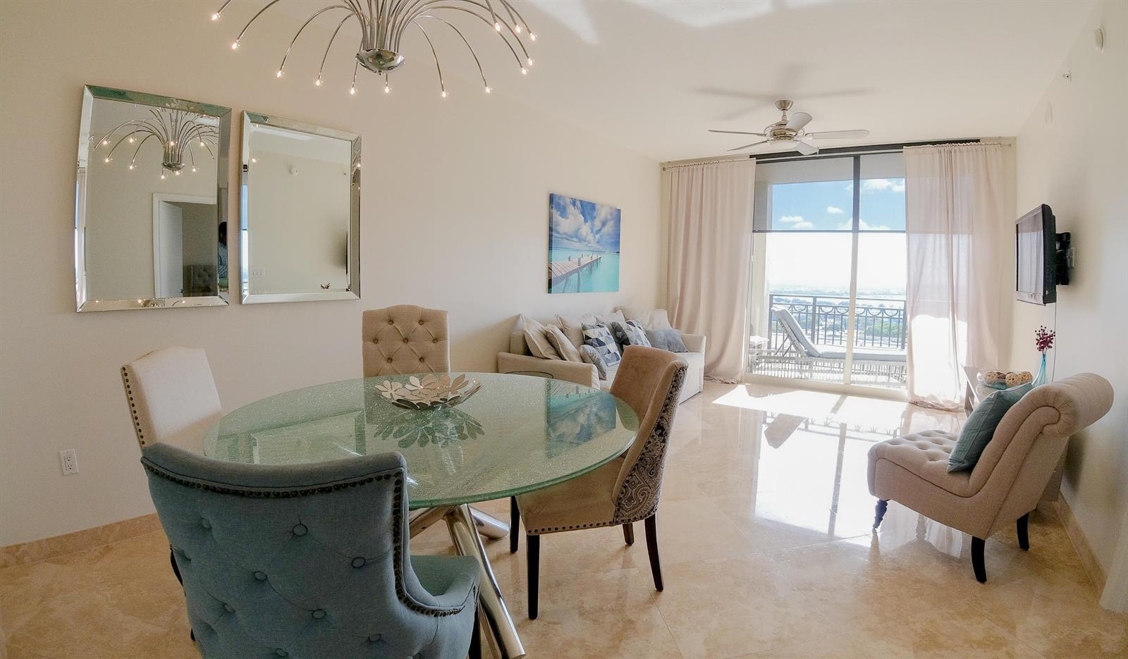 A dining area and living space feature a glass table, upholstered chairs, and balcony access — 550 Okeechobee Boulevard # 1721, West Palm Beach FL 33401, WEST PALM BEACH, FL