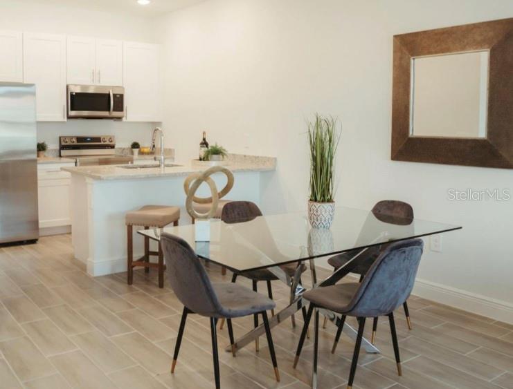 A kitchen with white cabinets and a dining area featuring a glass-topped table — 1740 PACIFIC ROAD, KISSIMMEE, FL