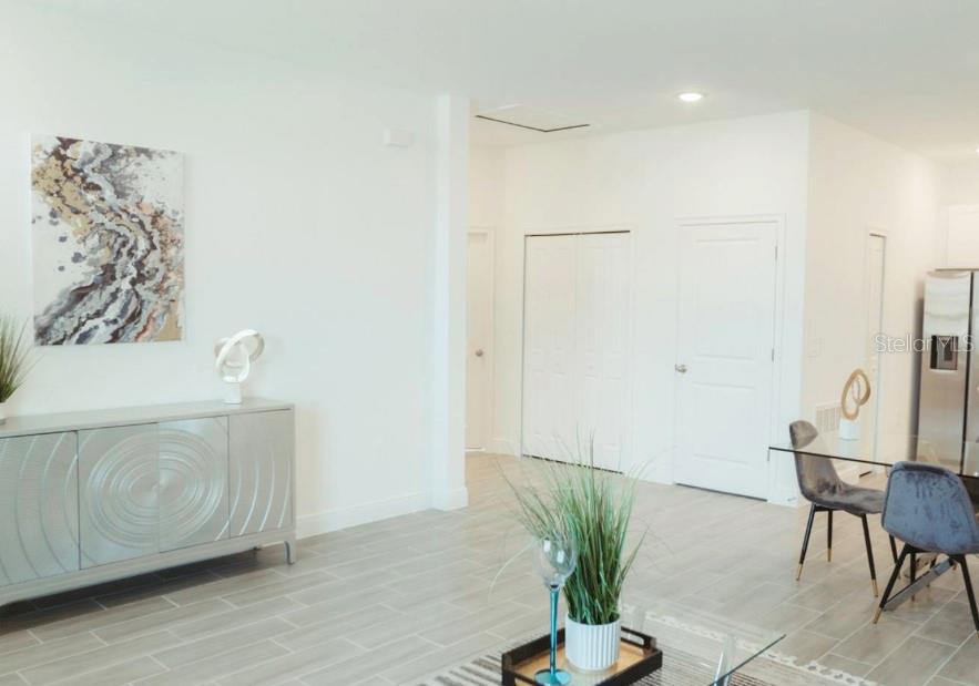 A bright, open-concept living and dining area features light tile flooring and white walls — 1740 PACIFIC ROAD, KISSIMMEE, FL