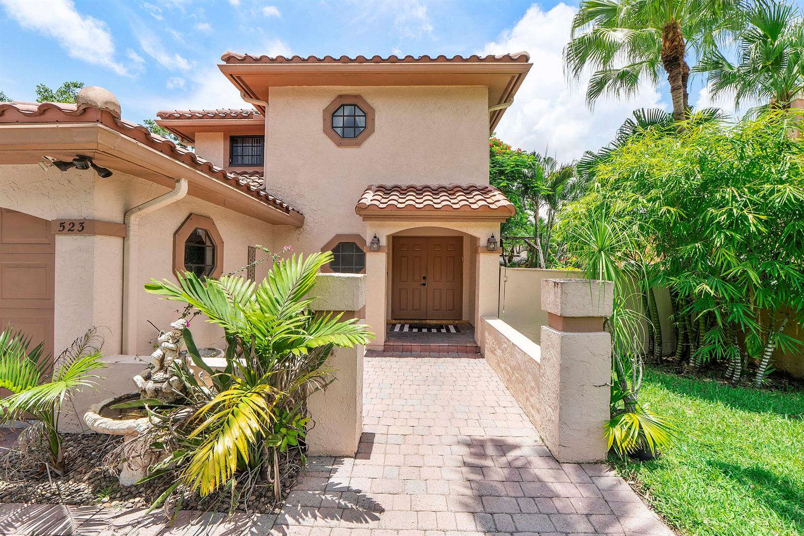 A two-story stucco house features a tiled roof, a brick walkway, and a front fountain — 523 NW 38th Terrace, Deerfield Beach FL 33442, DEERFIELD BEACH, FL