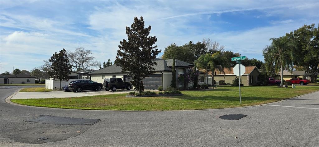A corner lot features a single-story house with a driveway, two parked vehicles, and landscaping — 336 LAKECREST DRIVE, TAVARES, FL