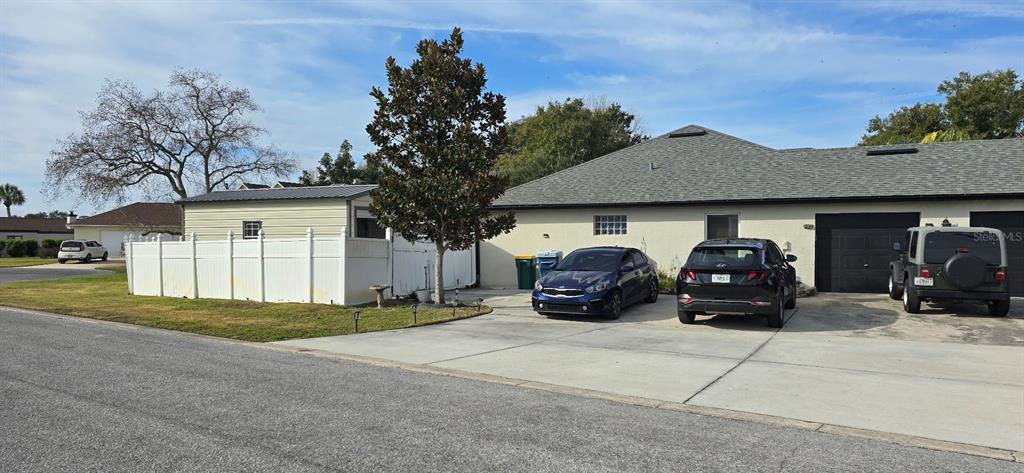 A single-story house with a concrete driveway, a white vinyl fence, and three parked vehicles — 336 LAKECREST DRIVE, TAVARES, FL