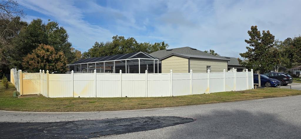 A white vinyl fence encloses the backyard and pool cage of a single-story suburban home — 336 LAKECREST DRIVE, TAVARES, FL