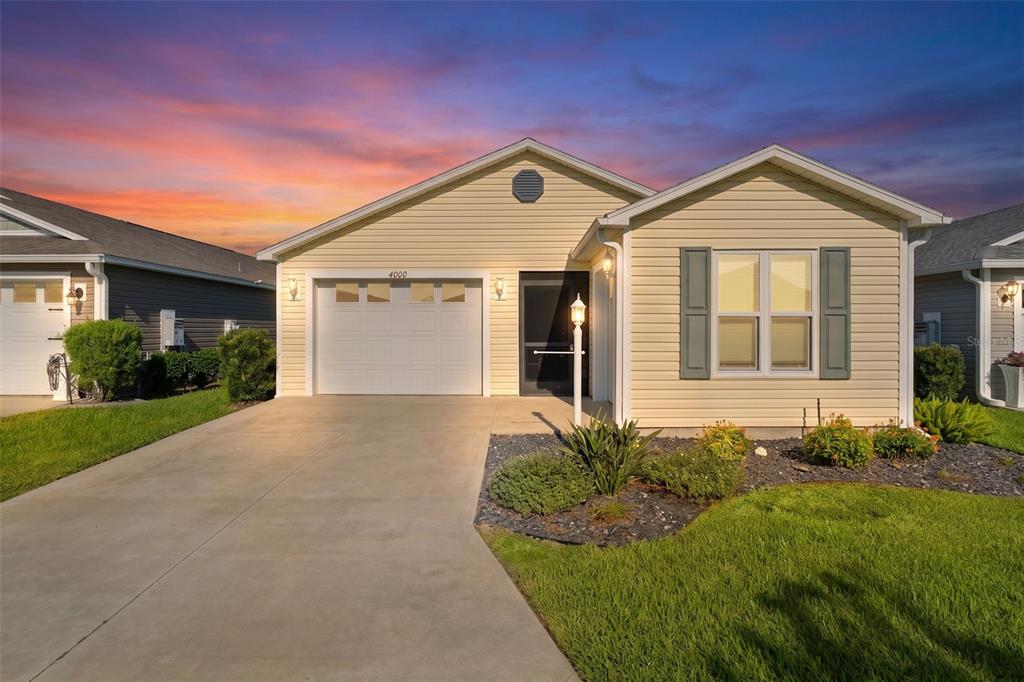 A single-story house with yellow siding, a white garage door, and a concrete driveway — 6080 ALLEN AVENUE, THE VILLAGES, FL
