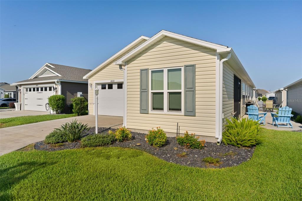 A light yellow single-story house features a garage, a front window with shutters, and landscaping — 6080 ALLEN AVENUE, THE VILLAGES, FL