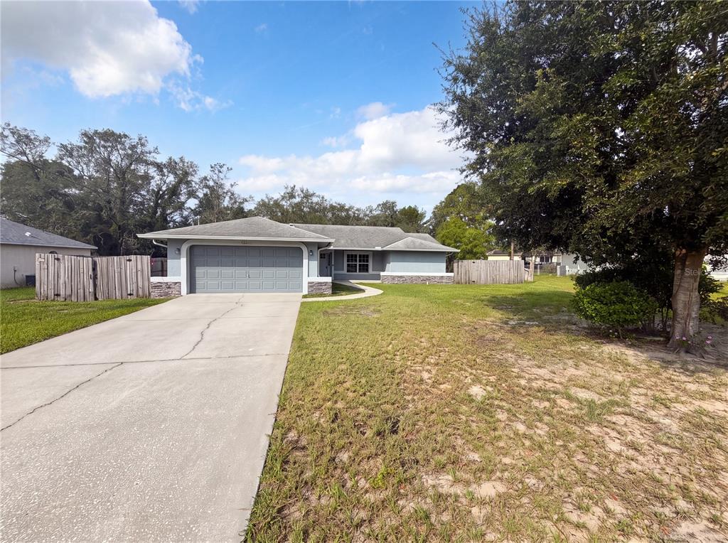 A single-story house with a gray garage, stone accents, and a concrete driveway — 3333 AGAR AVENUE, SPRING HILL, FL