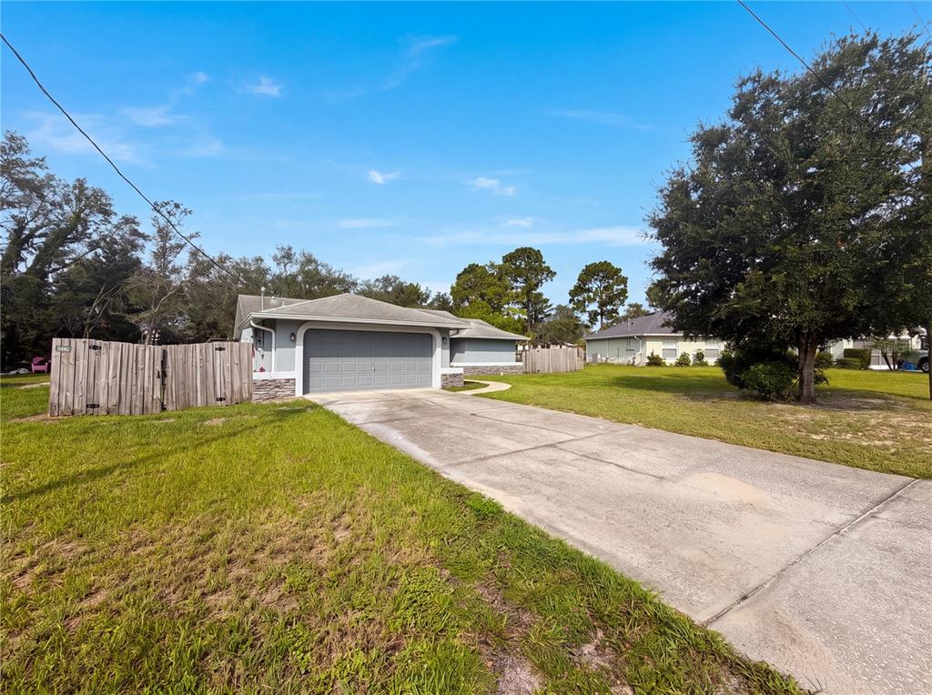 A single-story house with a gray garage door and a concrete driveway on a lawn — 3333 AGAR AVENUE, SPRING HILL, FL