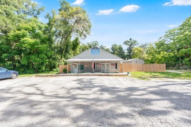 A single-story commercial building with a metal roof sits behind a large gravel parking lot — 123 W RHODE ISLAND AVENUE, ORANGE CITY, FL