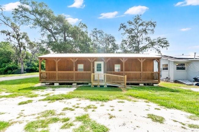 A single-story wooden cabin with a full-length front porch sits on a grassy lot — 123 W RHODE ISLAND AVENUE, ORANGE CITY, FL