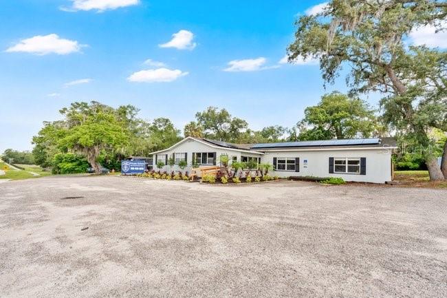 A single-story building with a gravel parking lot and solar panels on the roof — 123 W RHODE ISLAND AVENUE, ORANGE CITY, FL