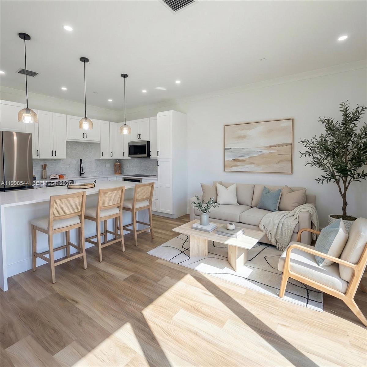 A bright open-concept kitchen and living area featuring white cabinetry, light wood floors, and furniture — 3609 Bal Harbor blvd, FL 33950, FL