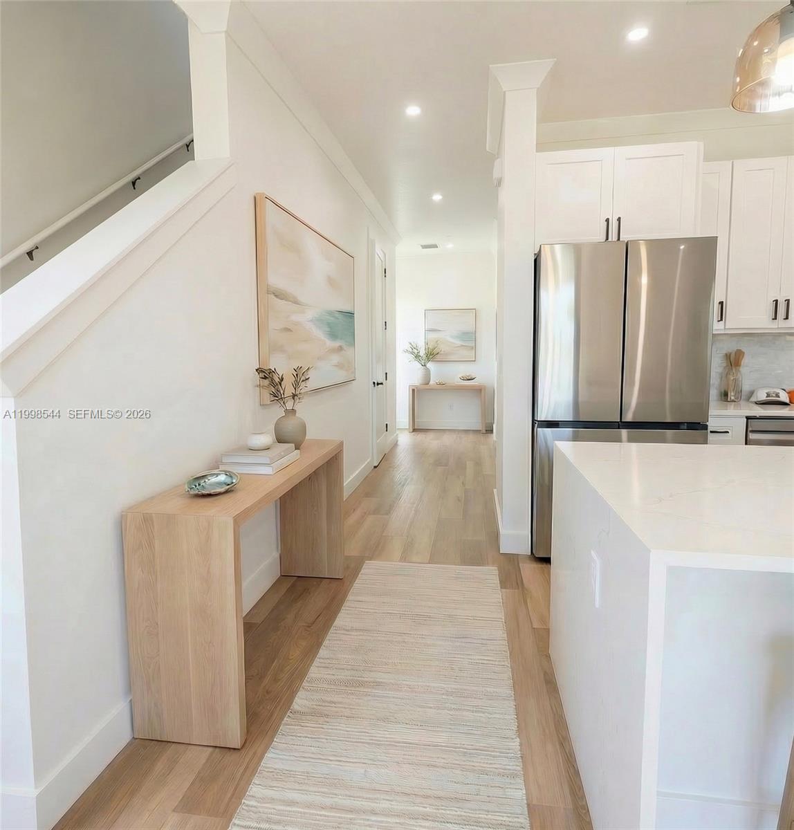 A hallway with light wood floors leads past a kitchen to a console table — 3609 Bal Harbor blvd, FL 33950, FL