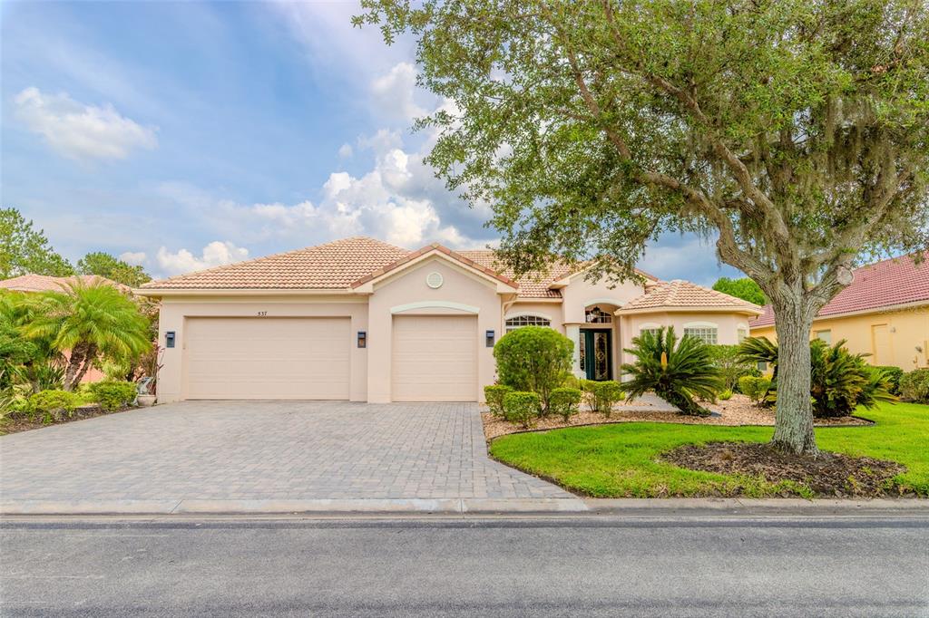A single-story house with a beige stucco exterior, tile roof, and a paved driveway — 537 MONTAGE LANE, KISSIMMEE, FL