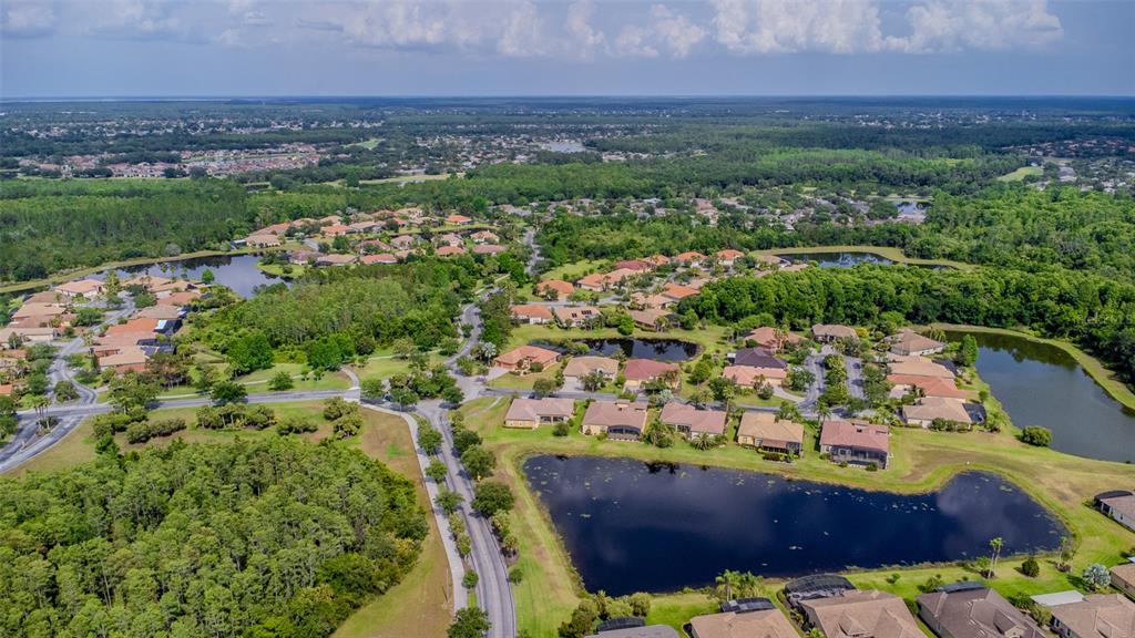 An aerial view shows a suburban neighborhood with houses surrounding several ponds and wooded areas — 537 MONTAGE LANE, KISSIMMEE, FL