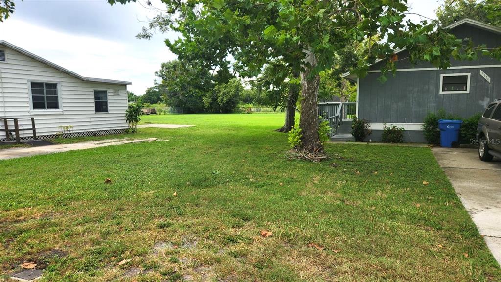 A grassy yard sits between a white house and a grey house with a driveway — 1114,1116,1118,1120&1128 WYATT  STREET, LARGO, FL
