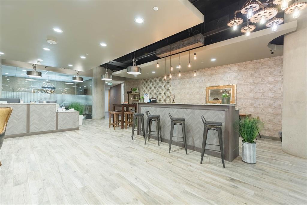 A modern office lobby features a long reception desk, bar-style seating, and industrial-style lighting fixtures — 400 N ASHLEY DRIVE UNIT 2605, TAMPA, FL