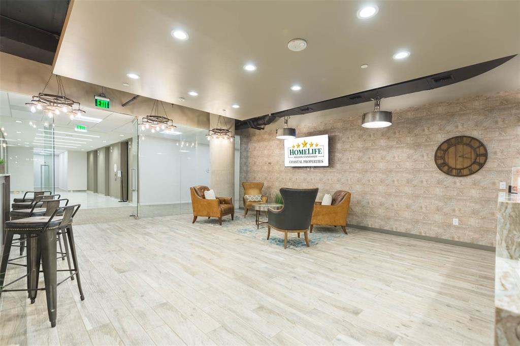 A modern office lobby features wood-look tile flooring, a seating area, and a branded wall sign — 400 N ASHLEY DRIVE UNIT 2605, TAMPA, FL