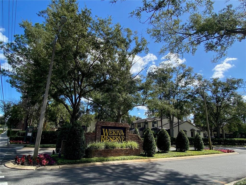 A brick entrance sign for Wekiva Reserve sits among trees and landscaping near a road — 2822 CANDELA COURT, APOPKA, FL