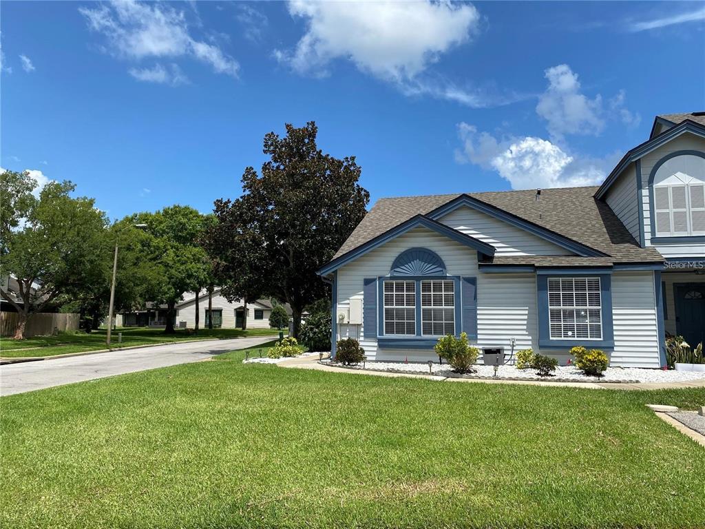 A light-colored house with blue trim and a shingled roof sits beside a grassy lawn — 2822 CANDELA COURT, APOPKA, FL