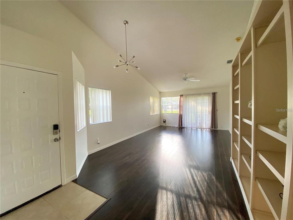 A living room features dark wood flooring, a vaulted ceiling, and built-in white shelving — 2822 CANDELA COURT, APOPKA, FL