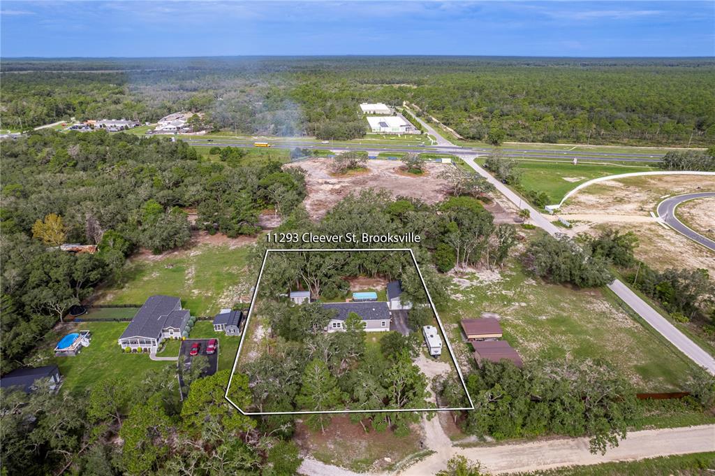 An aerial view shows a single-story house with a pool on a wooded lot — 11293 CLEEVER STREET, WEEKI WACHEE, FL